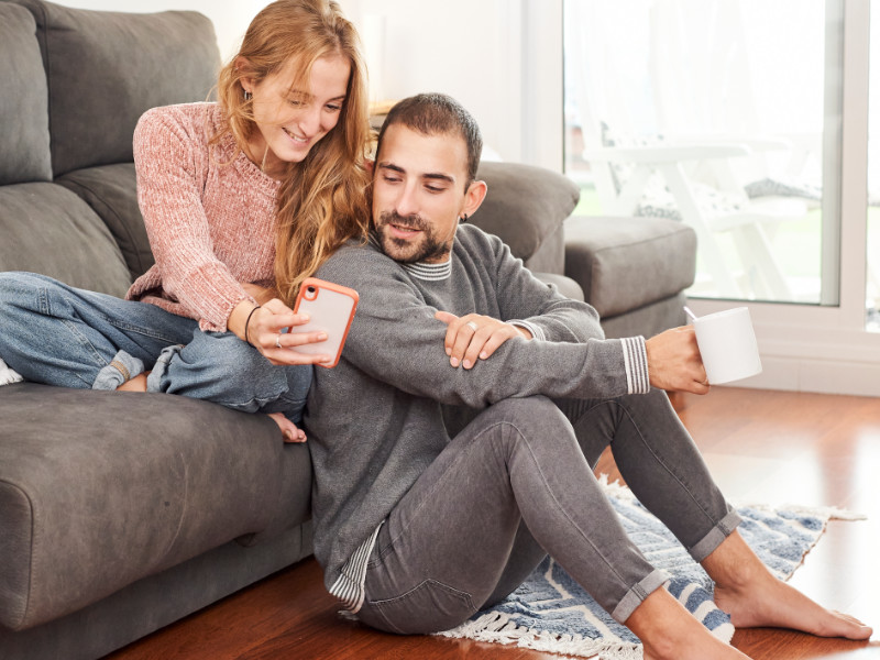 jonge man met blote voeten op de grond en zijn vriendin op de bank
